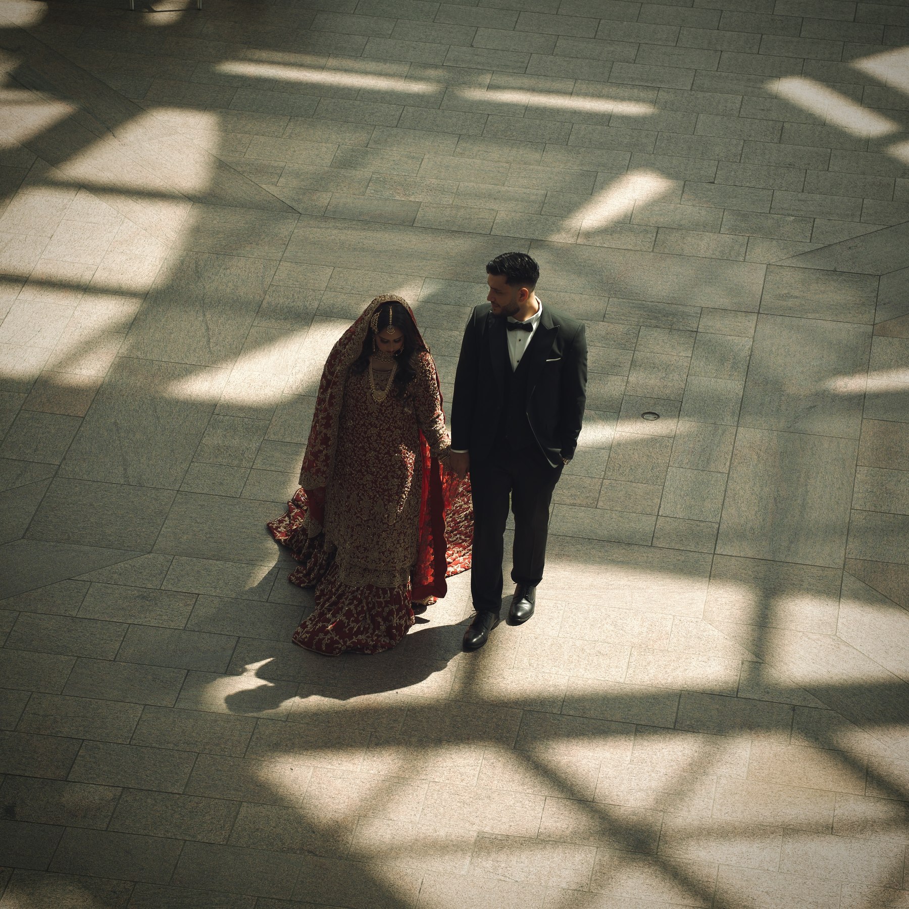 Aerial view of bride and groom walking through a sunlit atrium