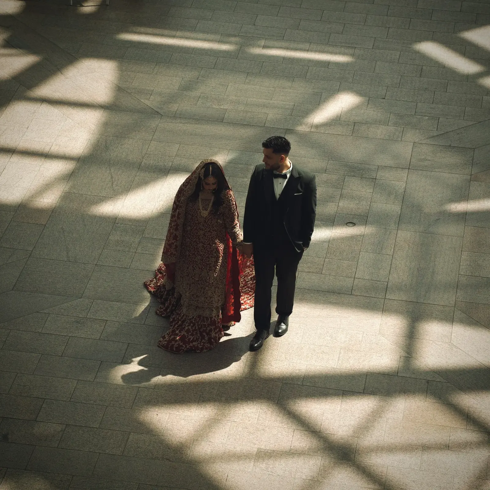 Aerial view of bride and groom walking through a sunlit atrium