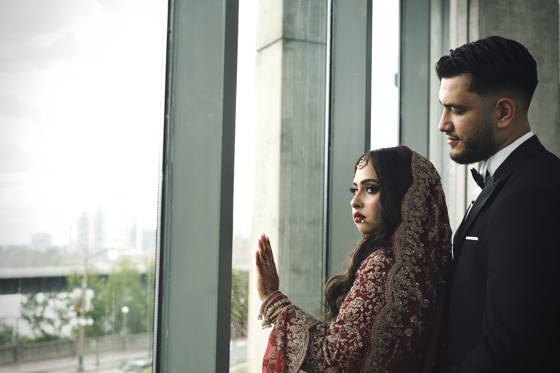 Bride and groom looking out a rain-streaked window