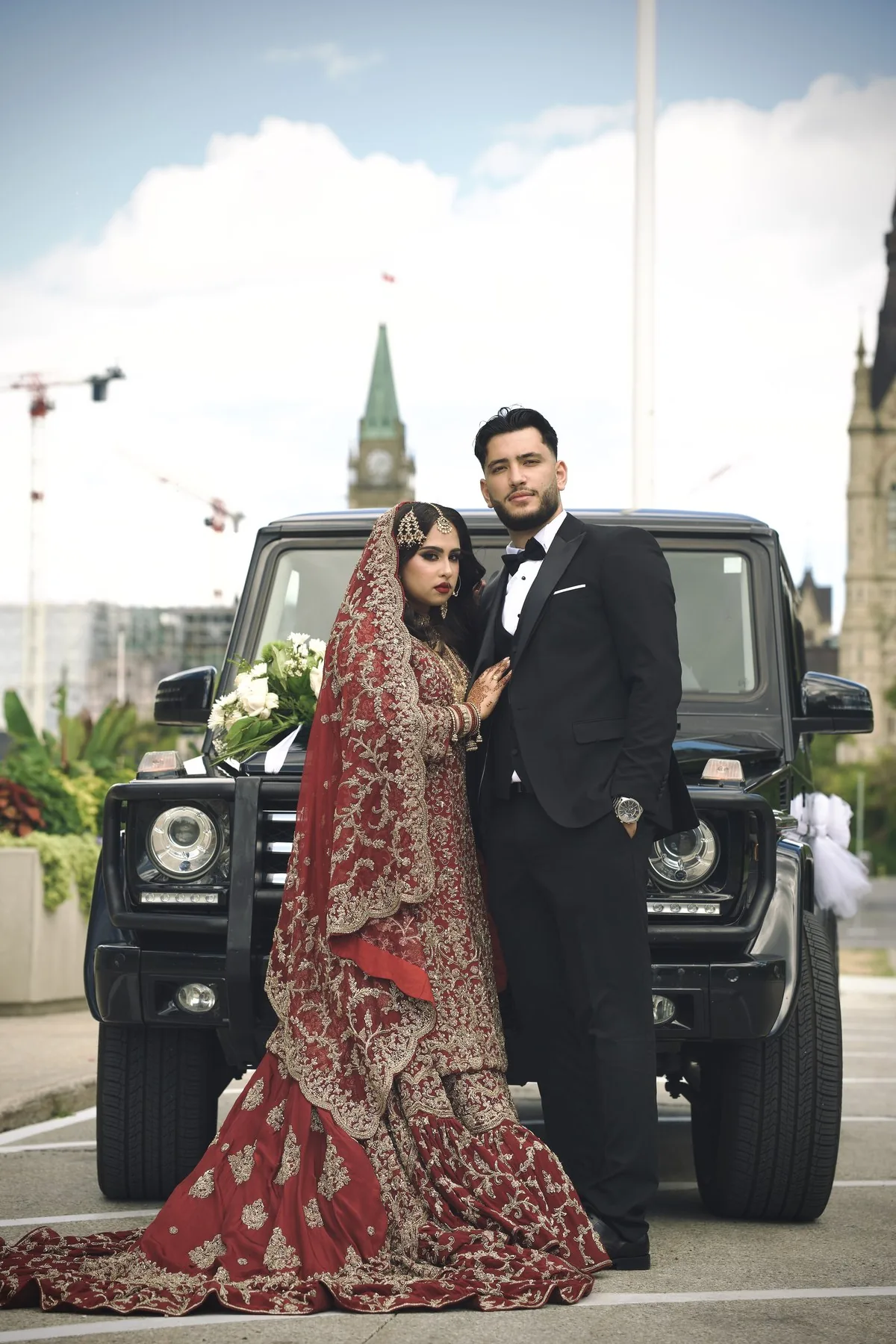 Couple in traditional formal attire beside a vintage car