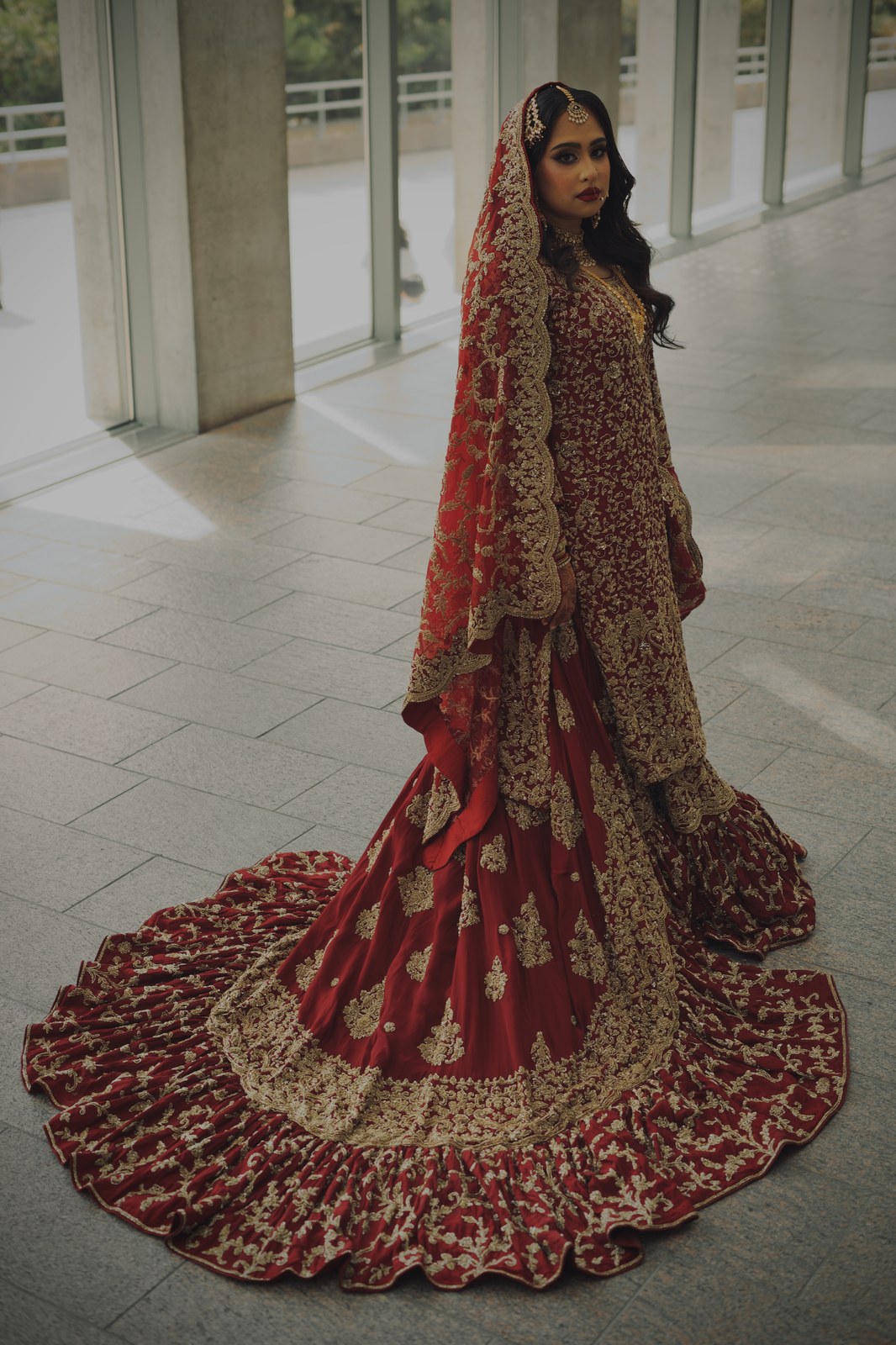 Bride in a formal red lehenga with an elaborate embroidered train