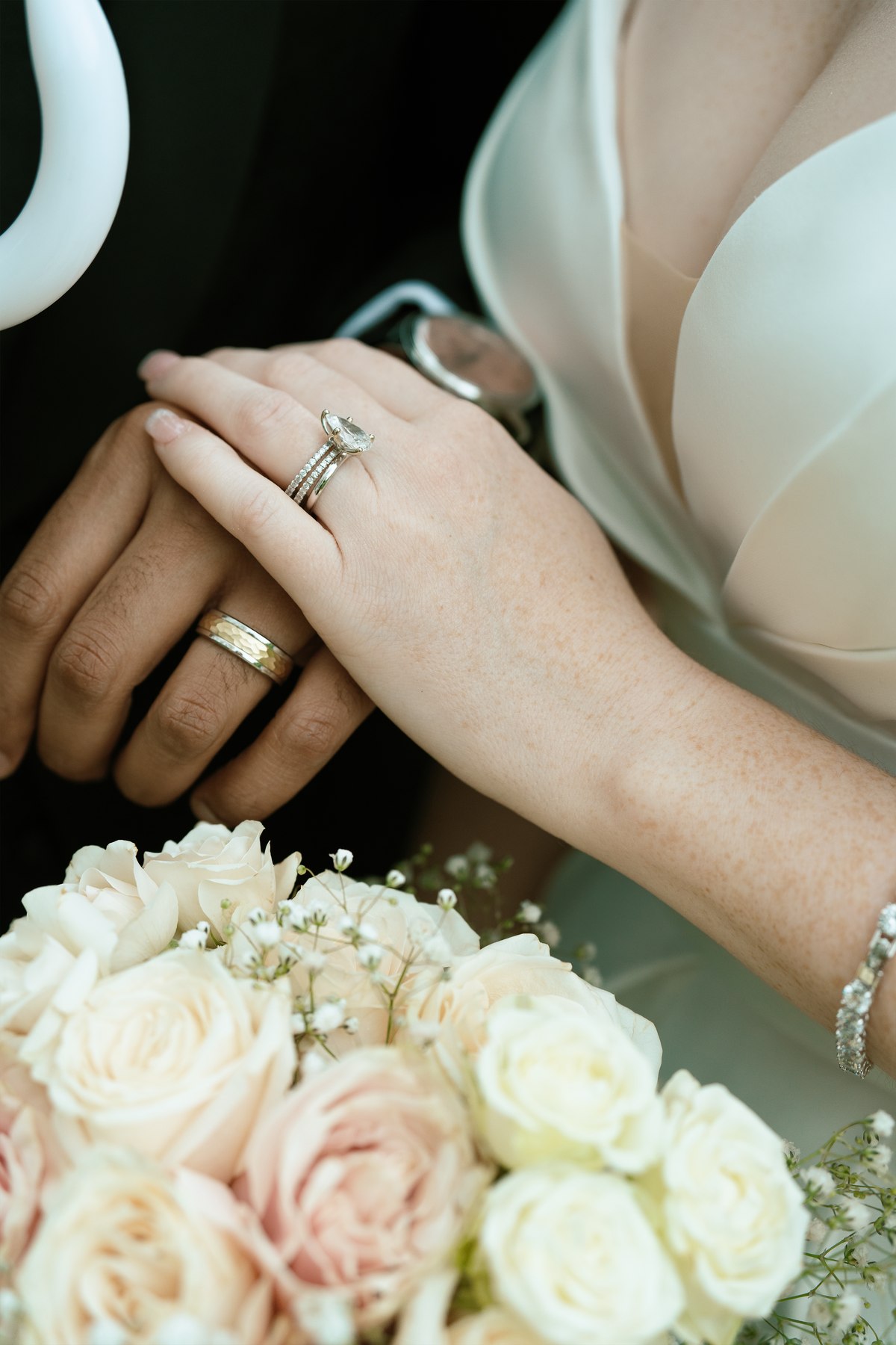 Bride and groom's hands with wedding rings, holding a bouquet